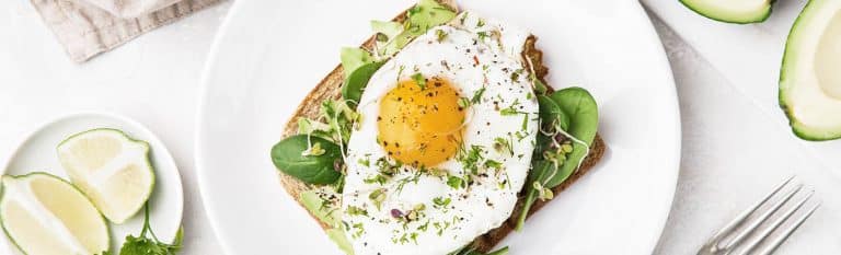 overhead shot of toast with avocado, spinach and fried egg