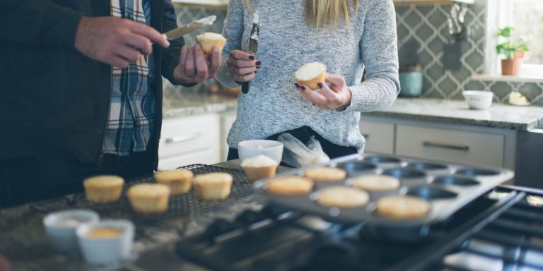 cropped image of a couple frosting cupcakes in a kitchen