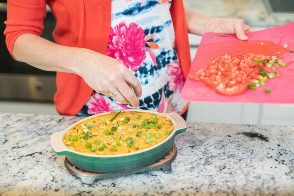 Cropped image of a woman adding toppings to a casserole