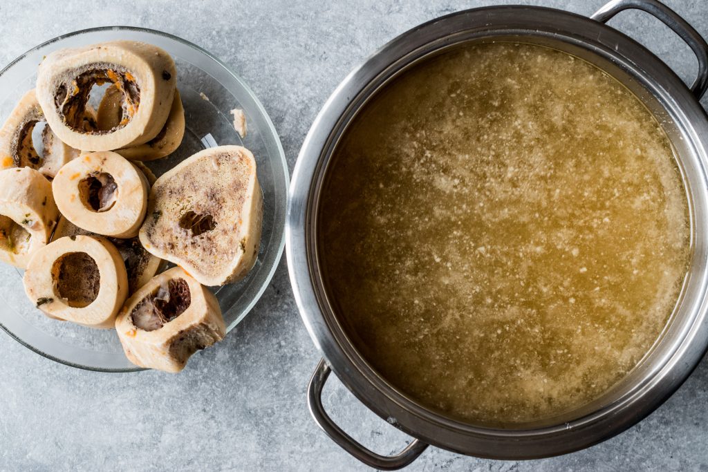 Bone Broth Bouillon in Metal Pan with beef bones on a plate next to it