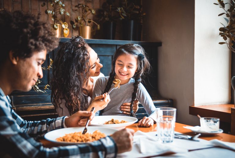 Happy african american family eating lunch together at restaurant and having fun