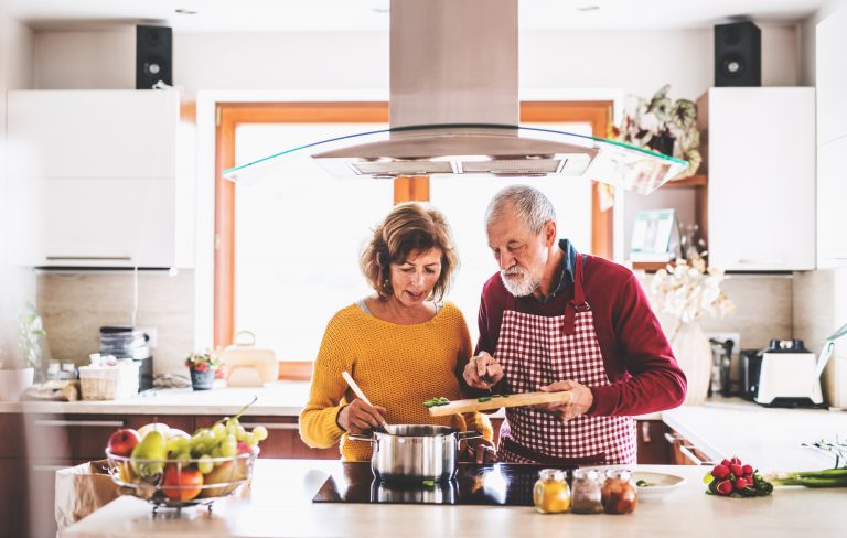 Senior couple preparing food in the kitchen. An old man and woman inside the house.