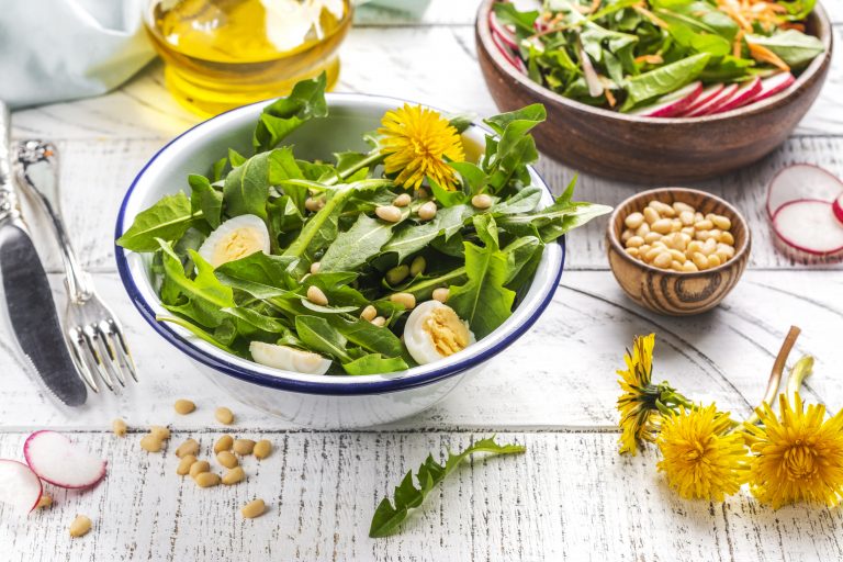 Fresh dandelion salad with nuts, boiled eggs and radish on white background.