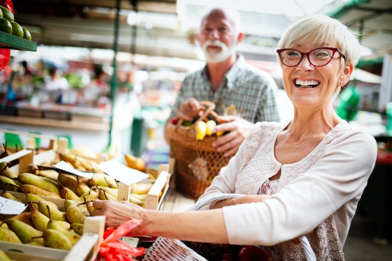 Portrait of beautiful elderly couple in market buing food