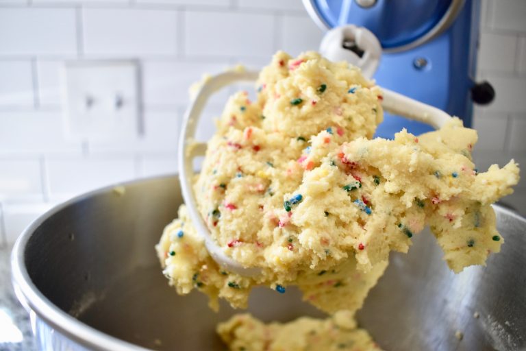 Cookie dough stuck to a mixer paddle on a stand mixer.