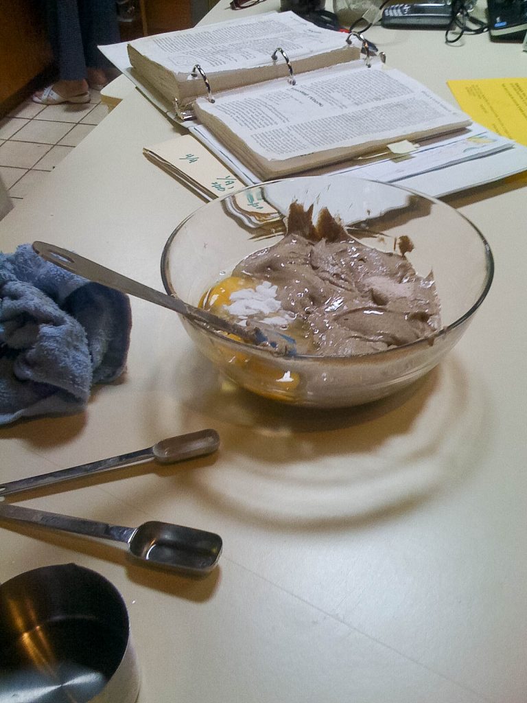 pancake batter in a glass bowl with recipe book open in background