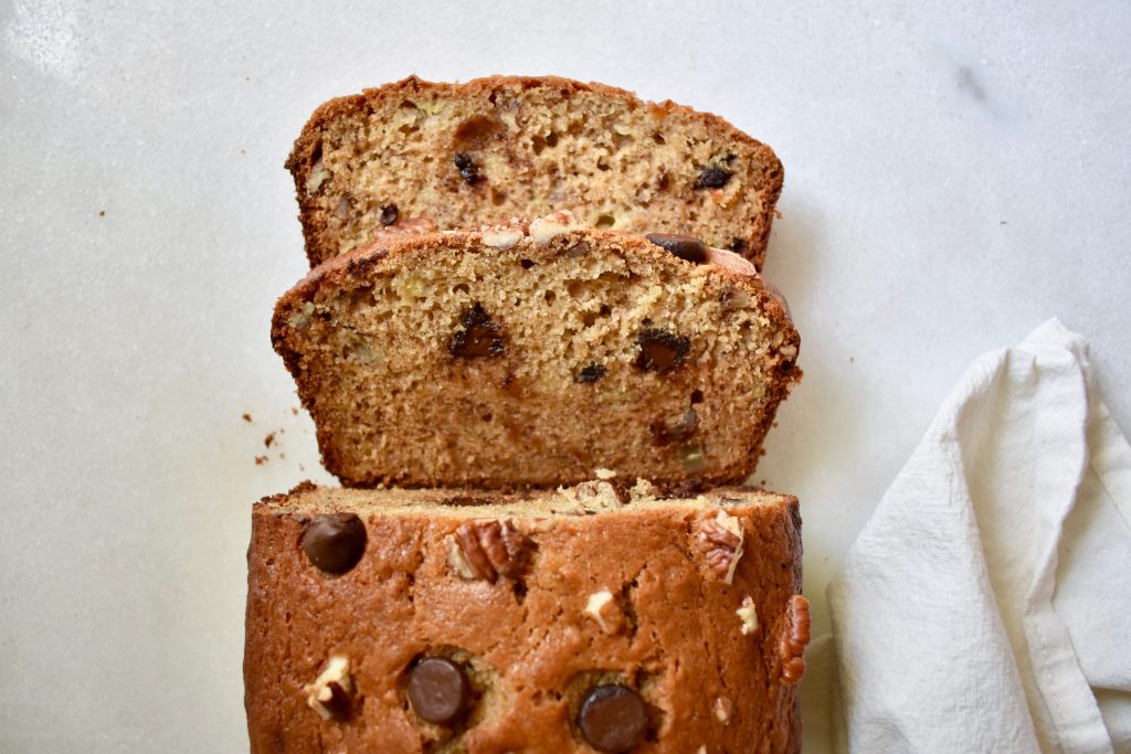 overhead shot of sliced banana bread loaf on white background