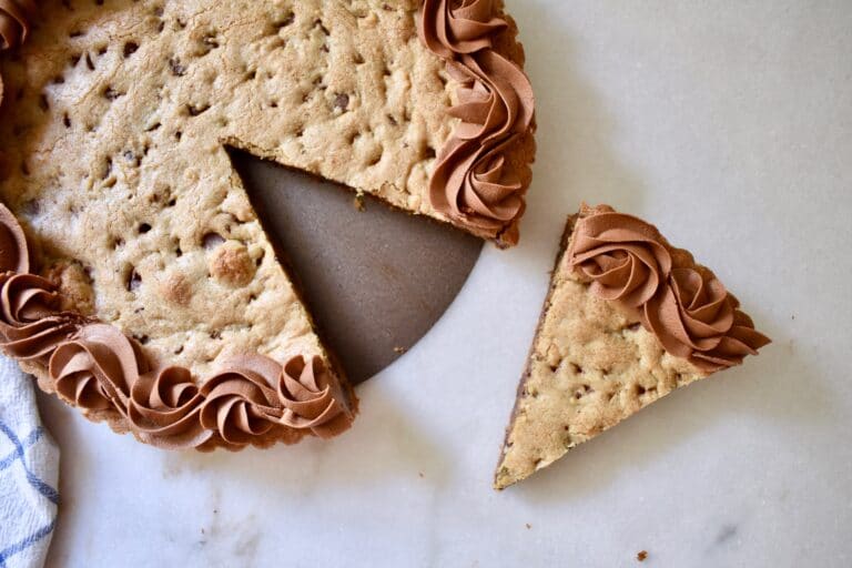 overhead shot of chocolate chip cookie cake with a slice cut out of it