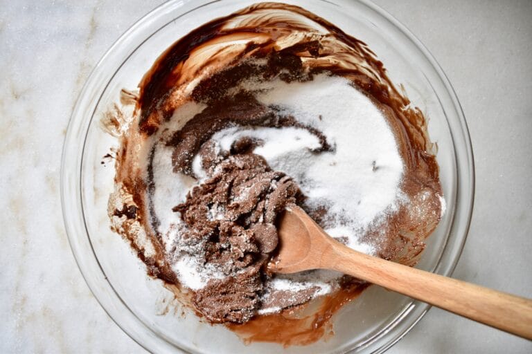 overhead shot of sugar being added to melted chocolate