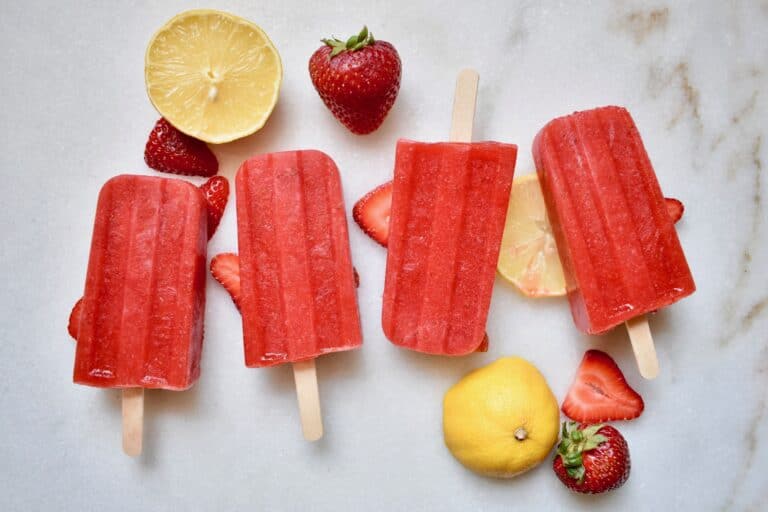 overhead shot of strawberry popsicles with lemons and strawberries around them