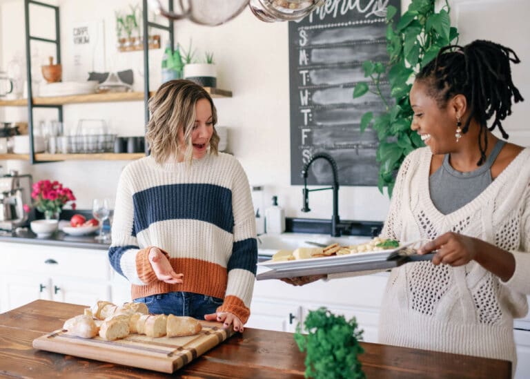 two women in a bright kitchen getting appetizers ready for a dinner party