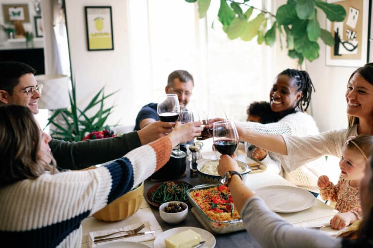 a group of friends cheersing wine glasses around a dinner table