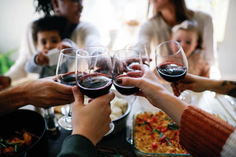 close up of wine glasses in a cheers around a dinner table