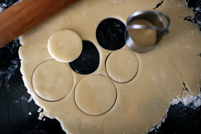 rolled out cookie dough with circular cookies cut out of it.