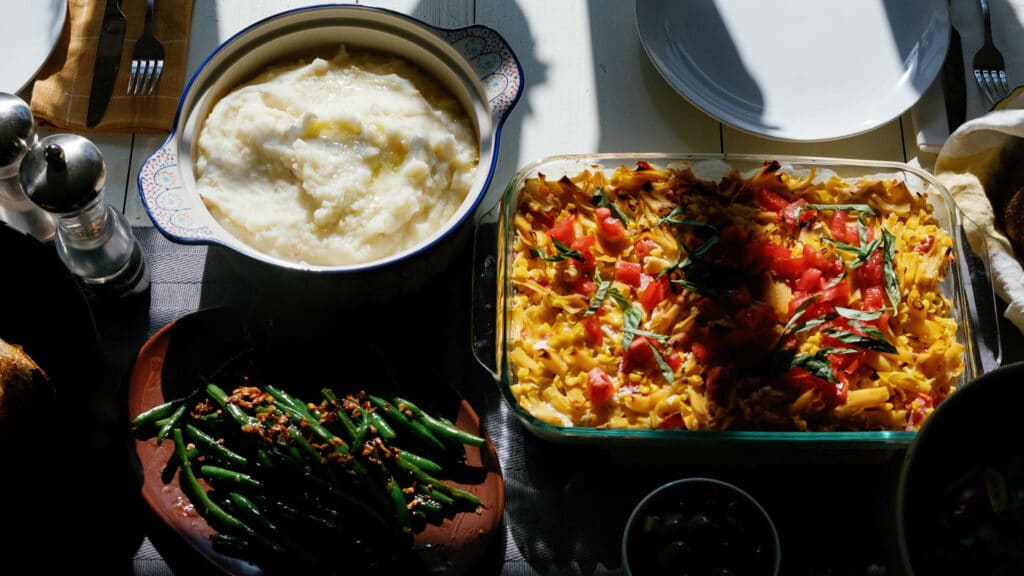 overhead shot of casserole, green beans and mashed potato side dishes on a dinner table