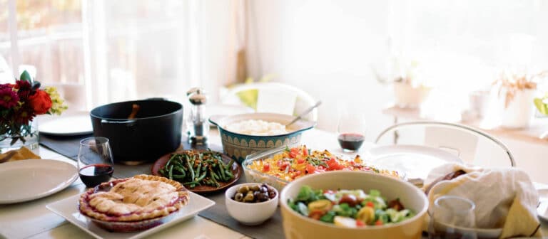 angled shot of a table filled with home cooked food, bright light shines in through a window